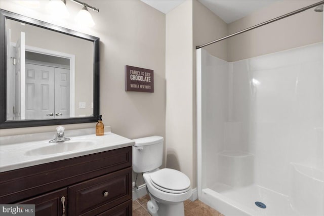 bathroom with tile patterned floors, vanity, toilet, and a shower