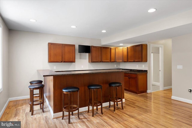 kitchen with a kitchen breakfast bar and light hardwood / wood-style floors