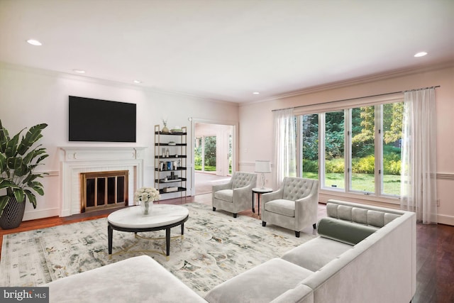 living room with ornamental molding, a brick fireplace, and hardwood / wood-style floors