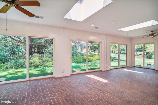 unfurnished sunroom featuring ceiling fan, a skylight, and plenty of natural light