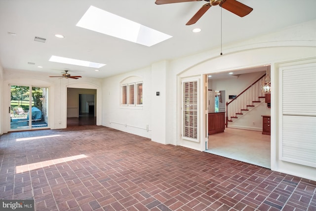 unfurnished living room featuring ceiling fan and a skylight