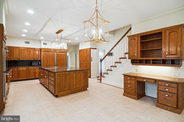 kitchen with built in desk, hanging light fixtures, an inviting chandelier, a center island with sink, and ornamental molding