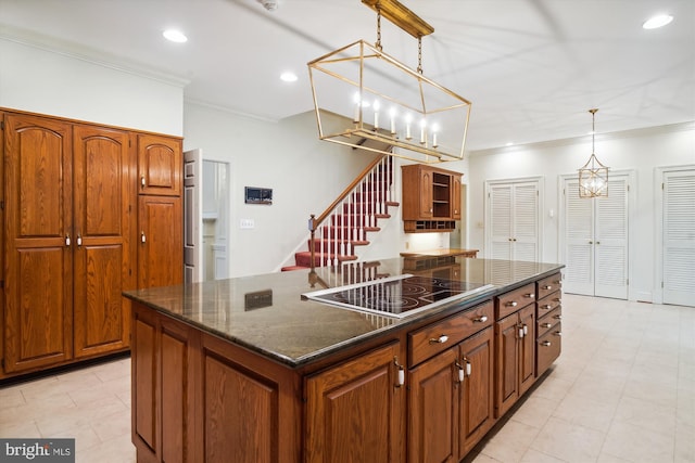 kitchen with pendant lighting, a center island, black electric stovetop, ornamental molding, and a notable chandelier