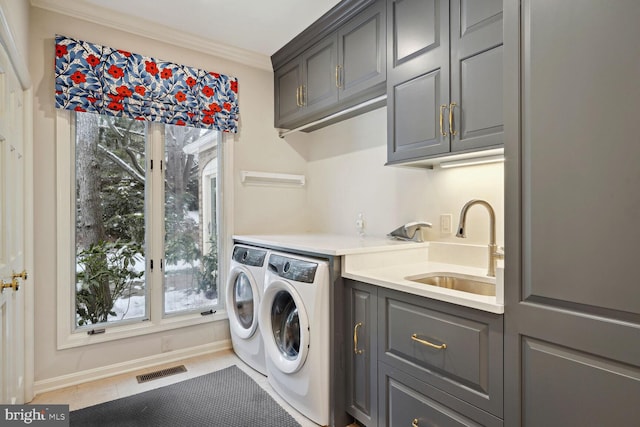 laundry area with cabinets, sink, washing machine and clothes dryer, tile patterned floors, and crown molding