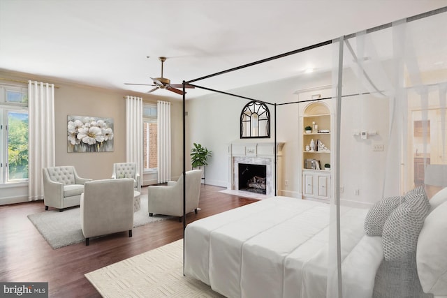 bedroom with ceiling fan, a premium fireplace, and hardwood / wood-style flooring