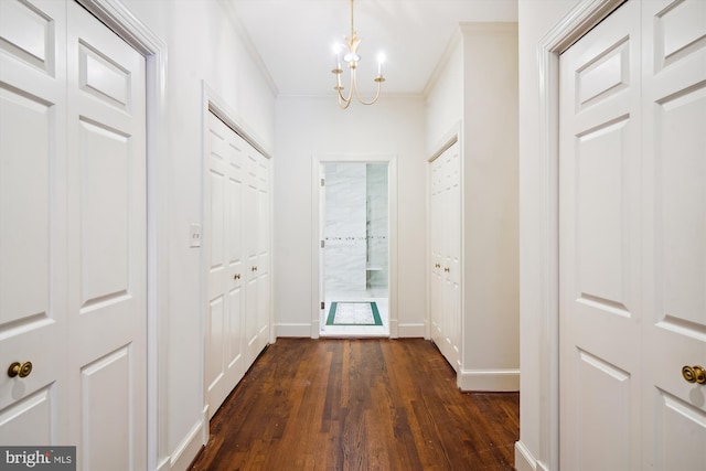 interior space with an inviting chandelier, crown molding, and dark wood-type flooring