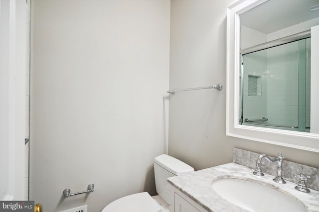 bathroom with vanity, toilet, and a shower with door