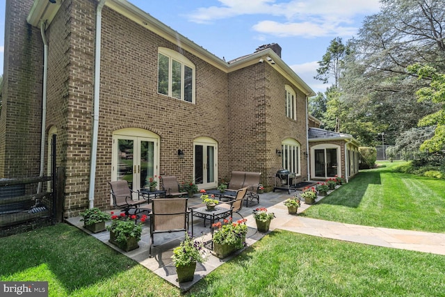 rear view of house with a patio area, french doors, and a yard