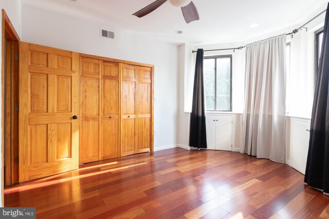 unfurnished bedroom with ceiling fan, a closet, and wood-type flooring