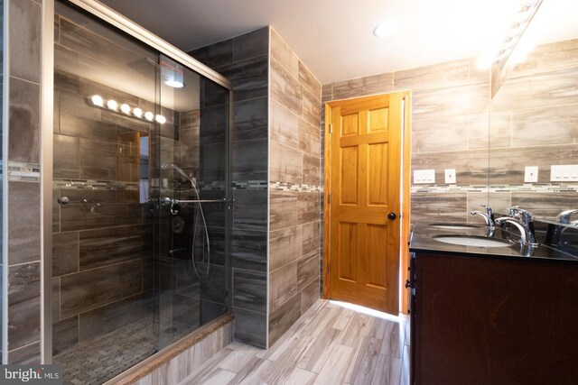 bathroom featuring vanity, an enclosed shower, tile walls, and hardwood / wood-style flooring