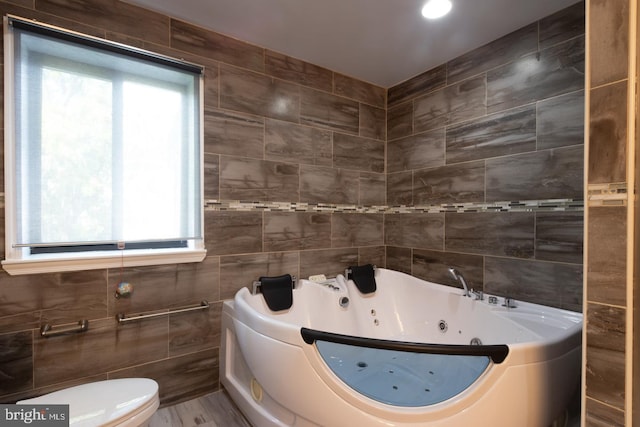 bathroom featuring plenty of natural light, toilet, tile walls, and a washtub