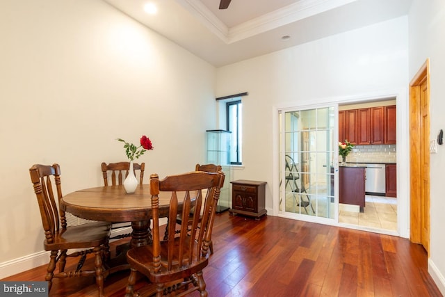 dining area featuring ornamental molding, a tray ceiling, and dark hardwood / wood-style floors