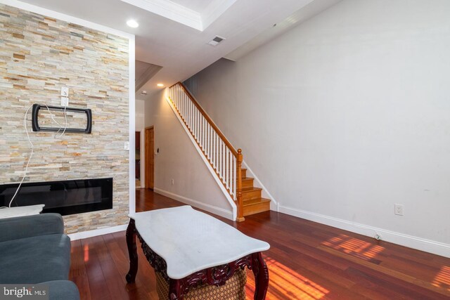 living room featuring a fireplace, crown molding, and dark hardwood / wood-style flooring