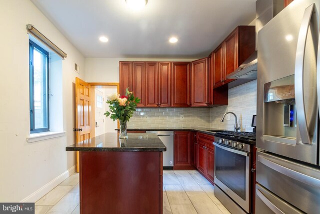 kitchen featuring dark stone countertops, appliances with stainless steel finishes, a wealth of natural light, and a center island