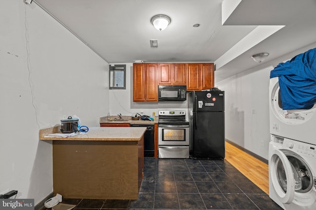 kitchen featuring black appliances, dark hardwood / wood-style floors, stacked washer / dryer, and sink