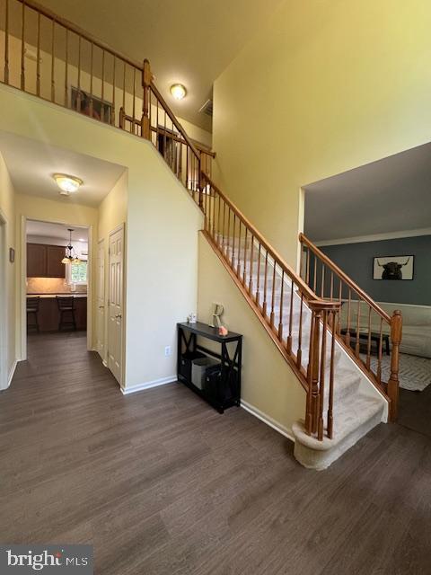 stairs with a high ceiling, wood finished floors, and baseboards