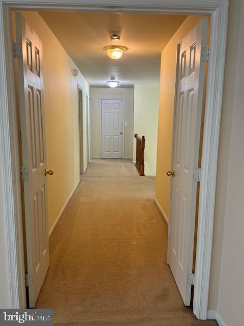 hallway featuring an upstairs landing and light colored carpet