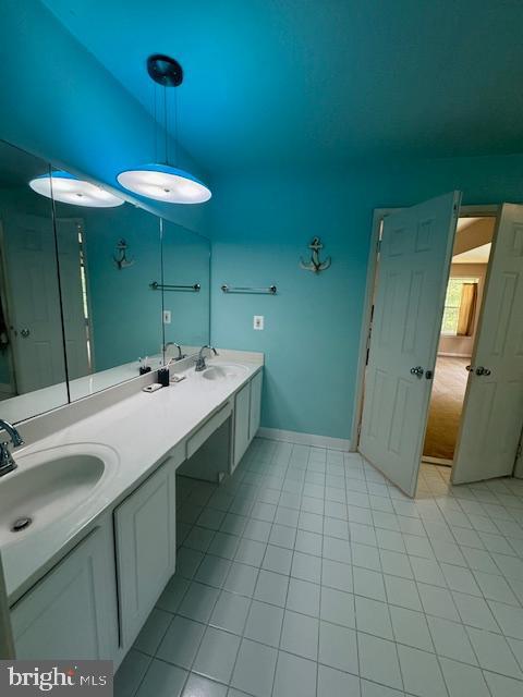 bathroom featuring double vanity, tile patterned flooring, baseboards, and a sink