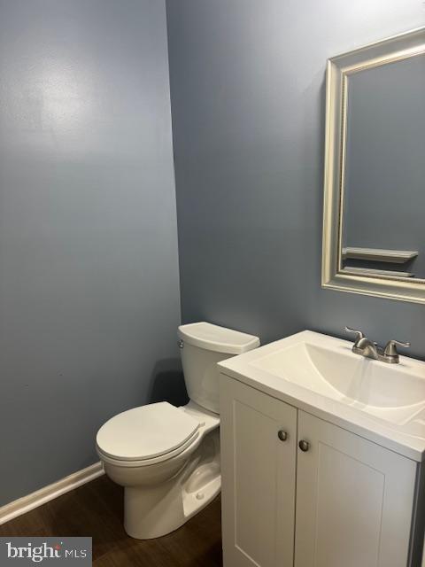 bathroom with toilet, baseboards, wood finished floors, and vanity