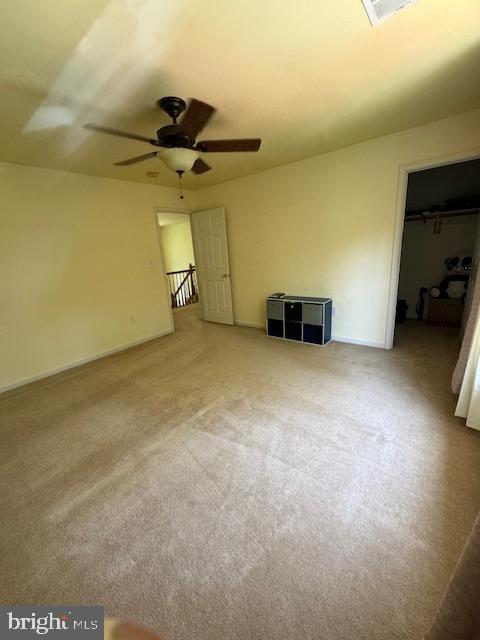 unfurnished bedroom featuring baseboards, ceiling fan, a spacious closet, carpet flooring, and a closet