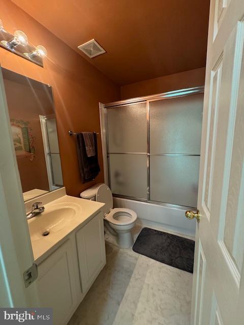 bathroom featuring toilet, combined bath / shower with glass door, vanity, and visible vents