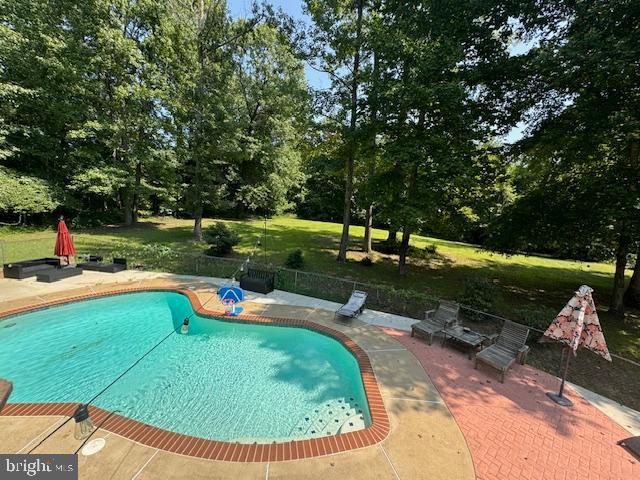 view of pool with a patio area, a lawn, fence, and a fenced in pool