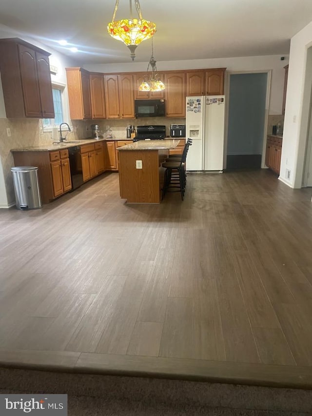 kitchen with dark wood-type flooring, a center island, light countertops, and black appliances