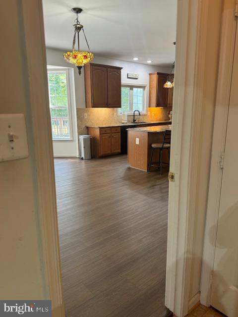 kitchen featuring a breakfast bar, dark wood-style flooring, light countertops, decorative backsplash, and decorative light fixtures