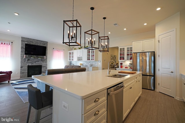 kitchen with a fireplace, white cabinetry, stainless steel appliances, and an island with sink