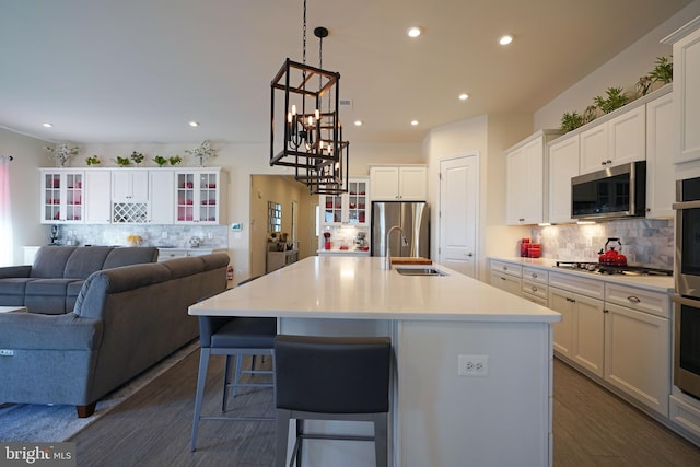 kitchen with an island with sink, sink, appliances with stainless steel finishes, and white cabinets