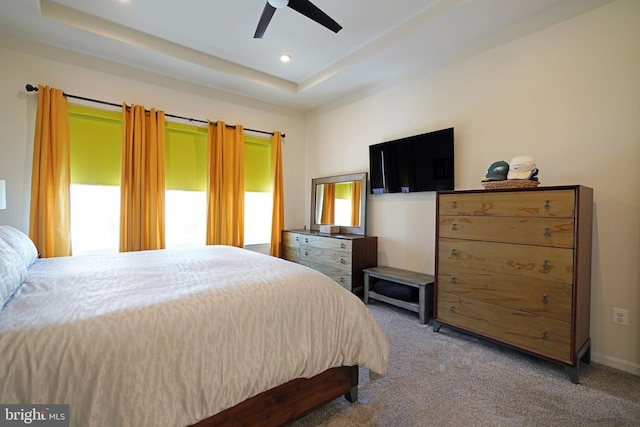 carpeted bedroom featuring ceiling fan and a tray ceiling