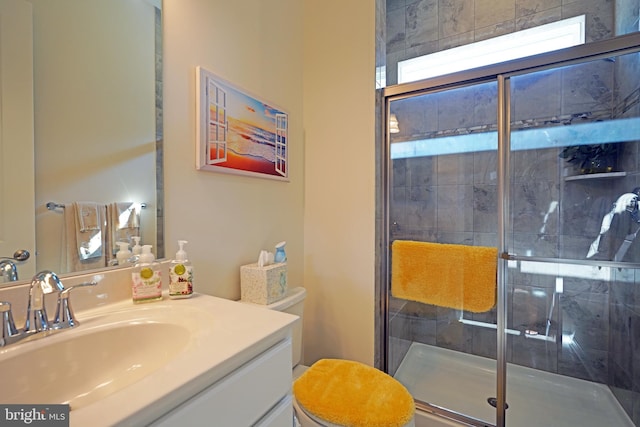 bathroom featuring toilet, a shower with door, and vanity