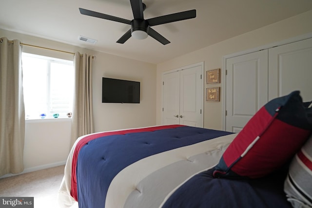 bedroom with carpet, ceiling fan, and multiple closets