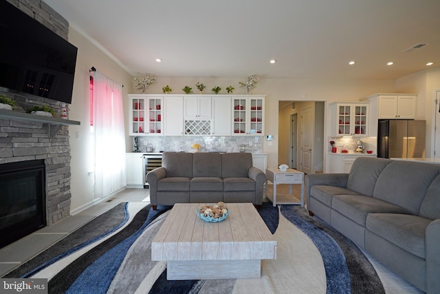 living room featuring wine cooler and a stone fireplace