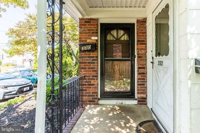 view of exterior entry with brick siding and covered porch