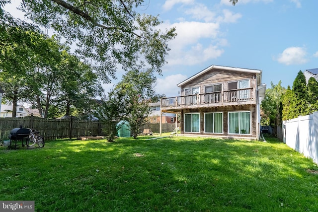 back of property with a deck, a lawn, and a fenced backyard