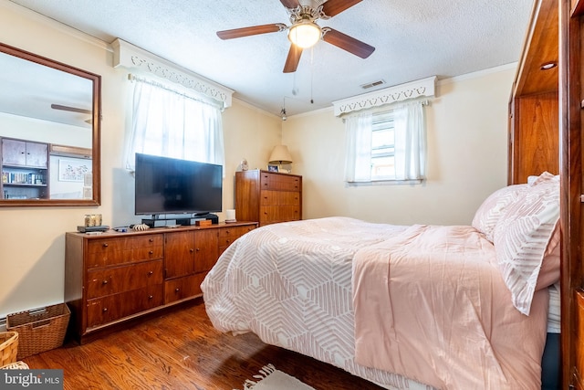 bedroom featuring a textured ceiling, ornamental molding, hardwood / wood-style floors, and ceiling fan