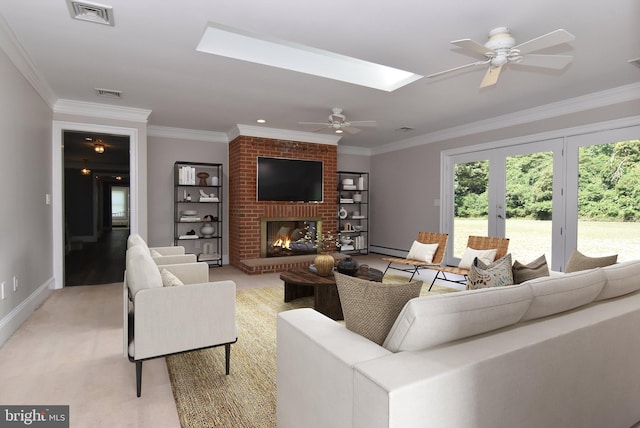 living room with a skylight, a fireplace, light colored carpet, ceiling fan, and ornamental molding