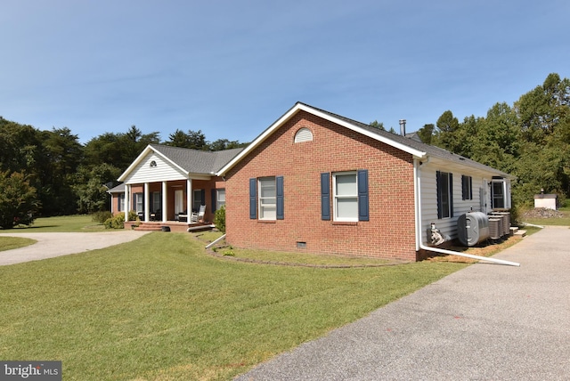 view of front of house with covered porch, a front lawn, and central AC