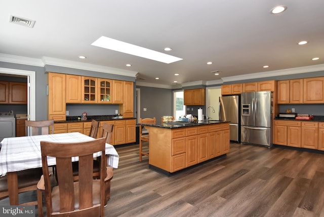 kitchen featuring a skylight, dark hardwood / wood-style floors, a center island with sink, and stainless steel refrigerator with ice dispenser