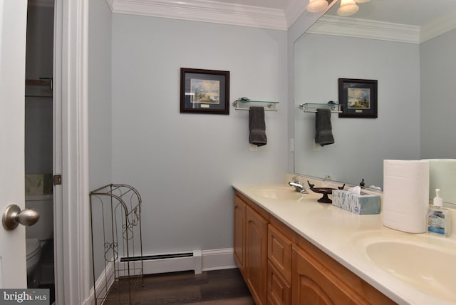 bathroom featuring a sink, wood finished floors, crown molding, double vanity, and baseboard heating