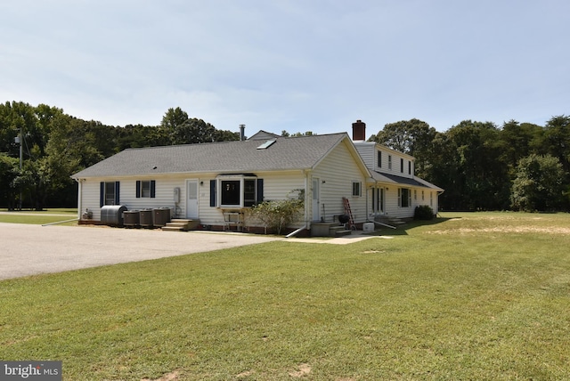 single story home with entry steps, a front lawn, and a chimney