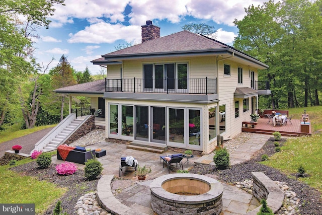 back of property featuring an outdoor fire pit, a patio area, a deck, and a balcony