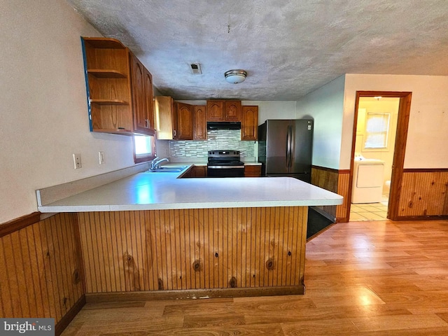 kitchen with electric range, visible vents, a wainscoted wall, washer / clothes dryer, and freestanding refrigerator