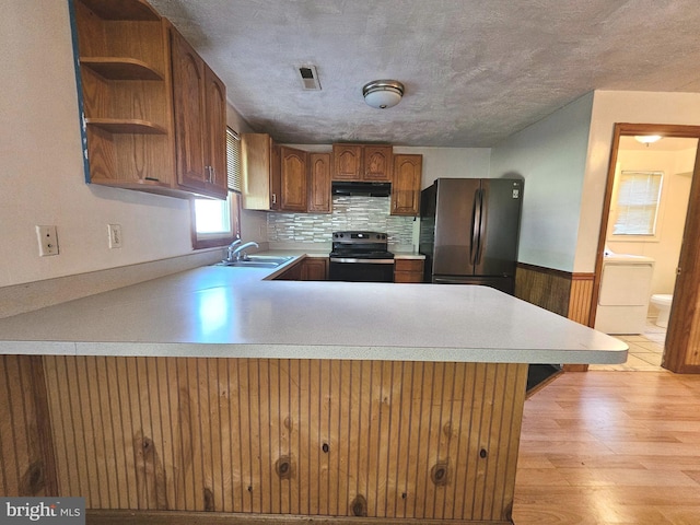 kitchen featuring visible vents, under cabinet range hood, a sink, freestanding refrigerator, and stainless steel electric range oven