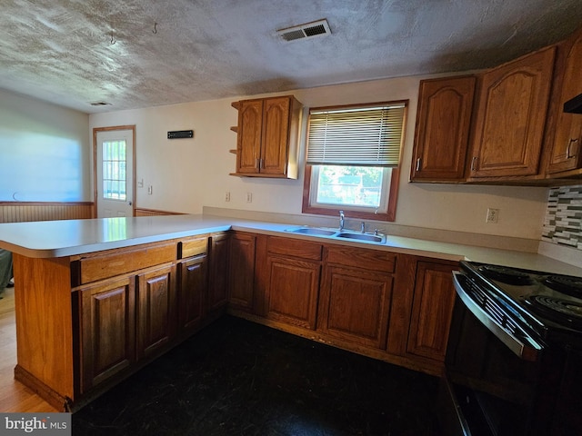 kitchen featuring visible vents, a peninsula, electric range, a sink, and a wealth of natural light