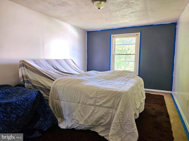 carpeted bedroom featuring baseboards and a textured ceiling