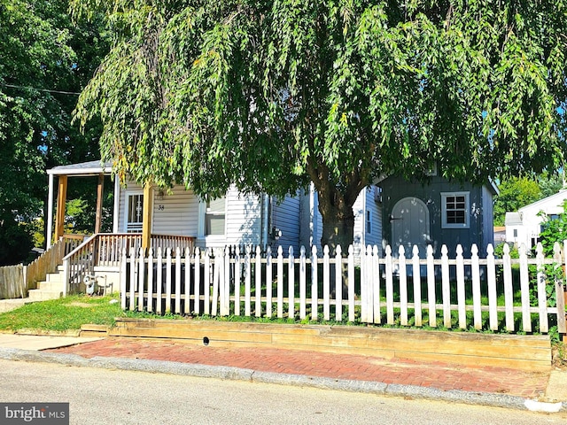 view of property hidden behind natural elements with a fenced front yard and covered porch