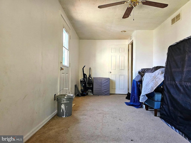 carpeted bedroom featuring ceiling fan, visible vents, and a textured ceiling