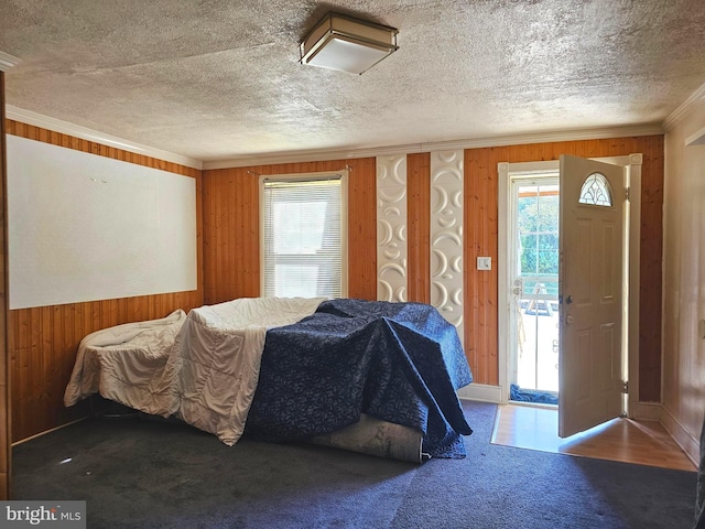 bedroom with a textured ceiling, carpet flooring, wood walls, and ornamental molding